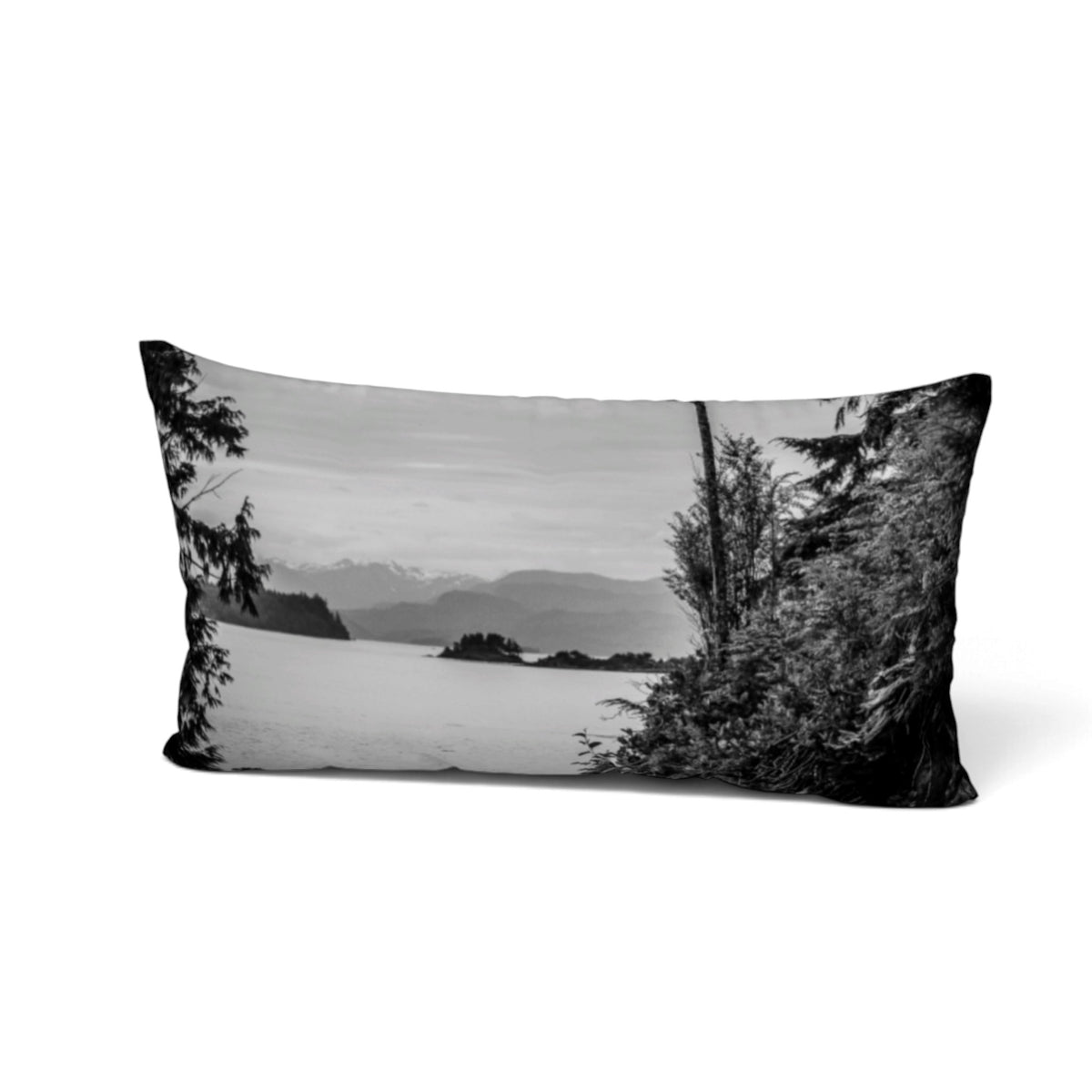 A rectangular lumbar throw pillow featuring a black and white landscape photograph of a lake, mountains, and evergreen trees, shown on a clean white background.