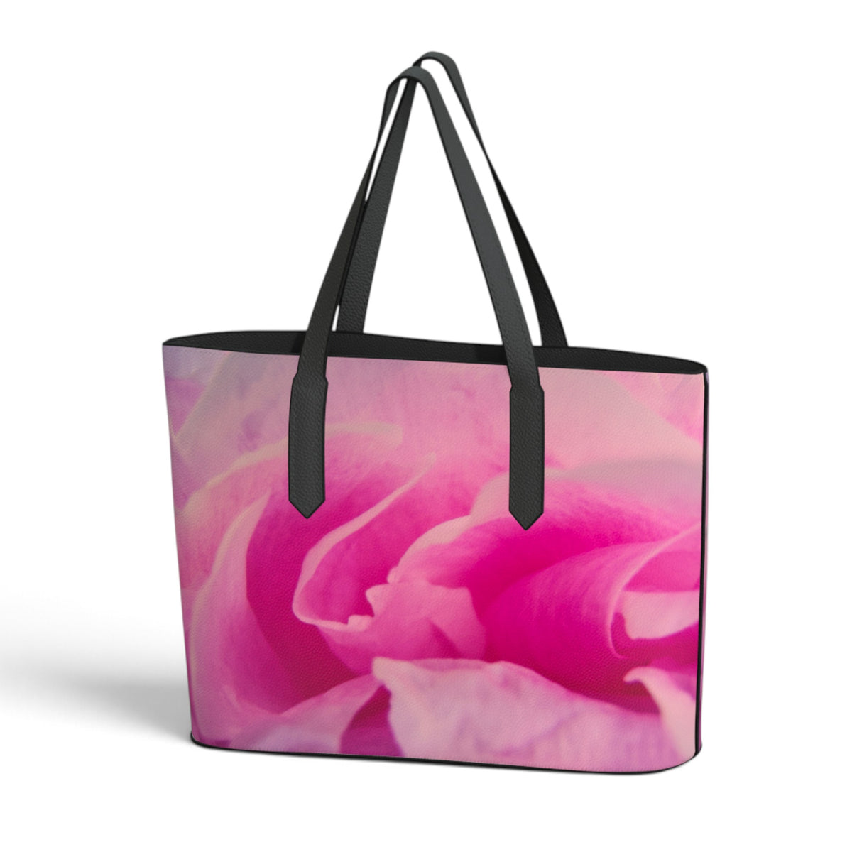 A tote bag featuring a close-up pink rose print on the front, with black handles and black trim, shown against a plain white background.