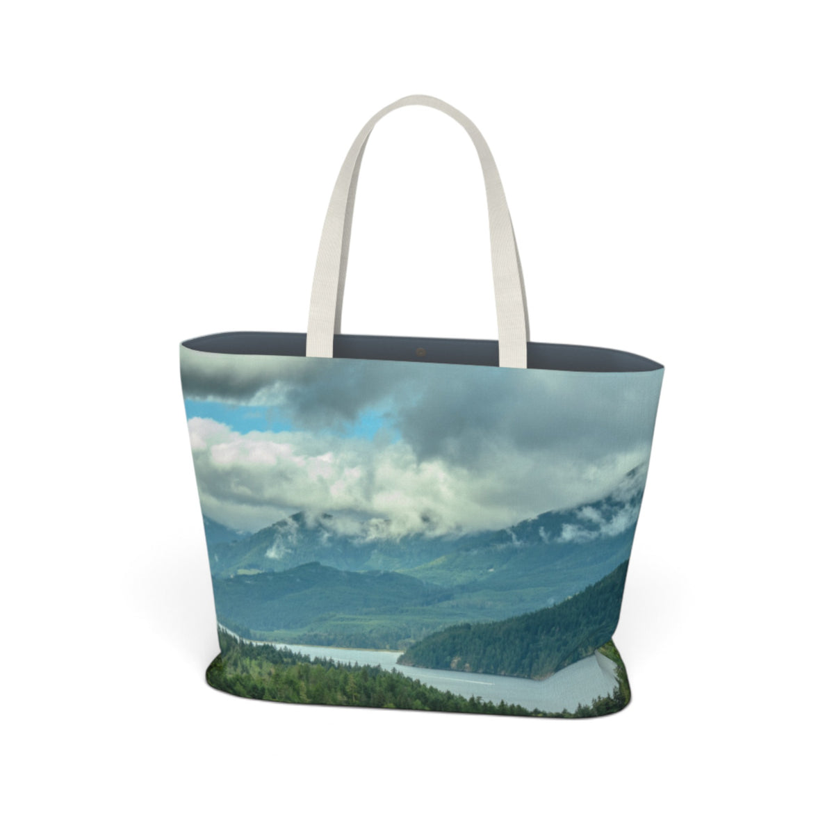 A tote bag featuring a scenic landscape print of mountains, clouds, and a lake, with off-white fabric shoulder straps, shown on a plain white background.