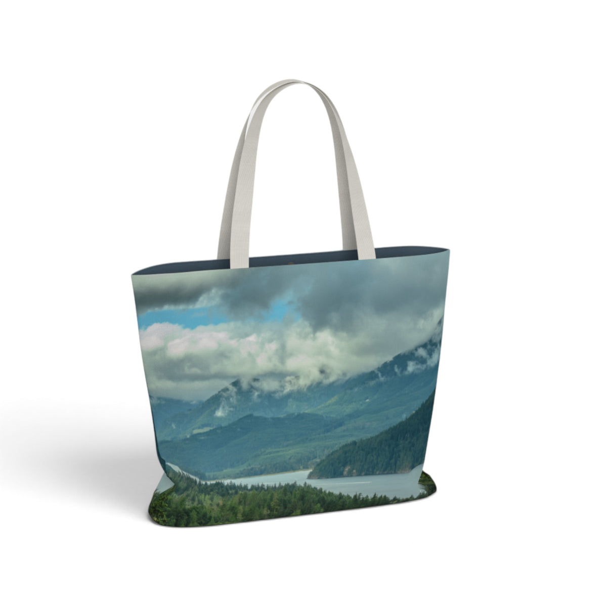 A tote bag featuring a scenic landscape print of mountains, clouds, and a lake, with light gray fabric shoulder straps, shown on a plain white background.