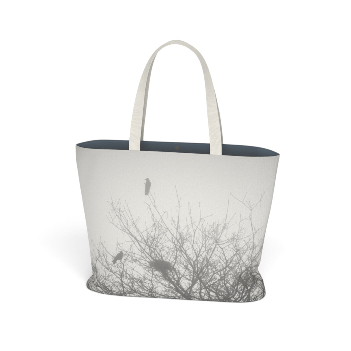 A tote bag with a minimalist black and white print of bare tree branches and birds, featuring off-white shoulder straps and a dark navy blue interior, shown on a clean white background.