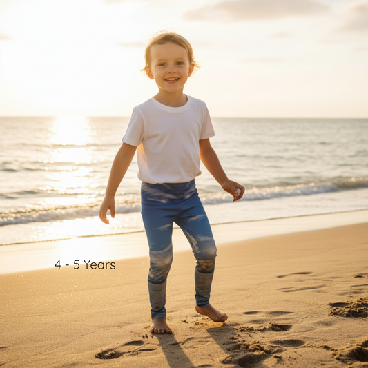 Child standing on a beach with ocean waves in the background