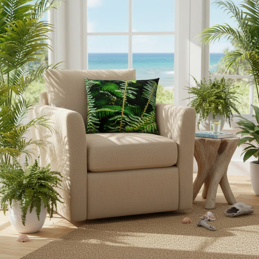 A beige upholstered armchair in a bright coastal room, styled with a green tropical fern-pattern throw pillow. The chair is positioned next to a rustic wooden side table with potted ferns, with a large window behind it showing a view of the ocean.
