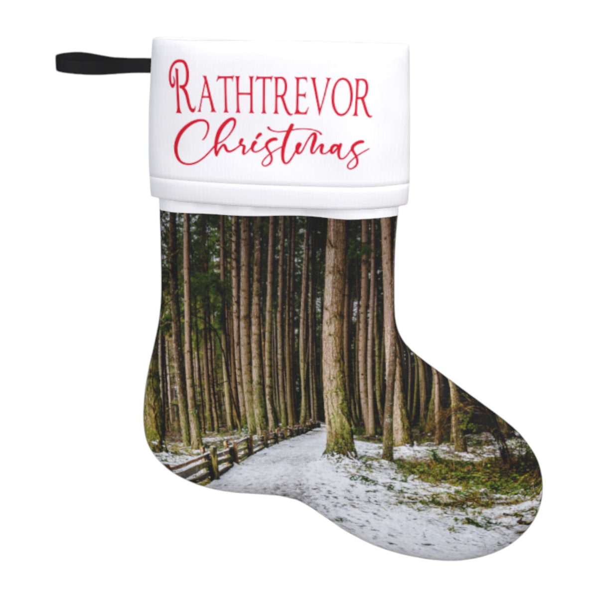 A Christmas stocking with a white cuff printed with the words 'RATHTREVOR Christmas' in red, and the body printed with a forest scene showing tall trees, a snowy path, and a wooden fence.