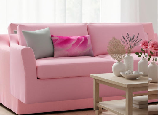 A pink upholstered sofa in a bright living room setting, styled with two decorative throw pillows and a small wooden coffee table in front.