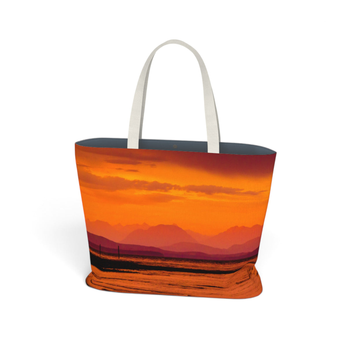 A tote bag featuring a vibrant orange and red sunset landscape print, with white shoulder straps, shown on a plain white background.