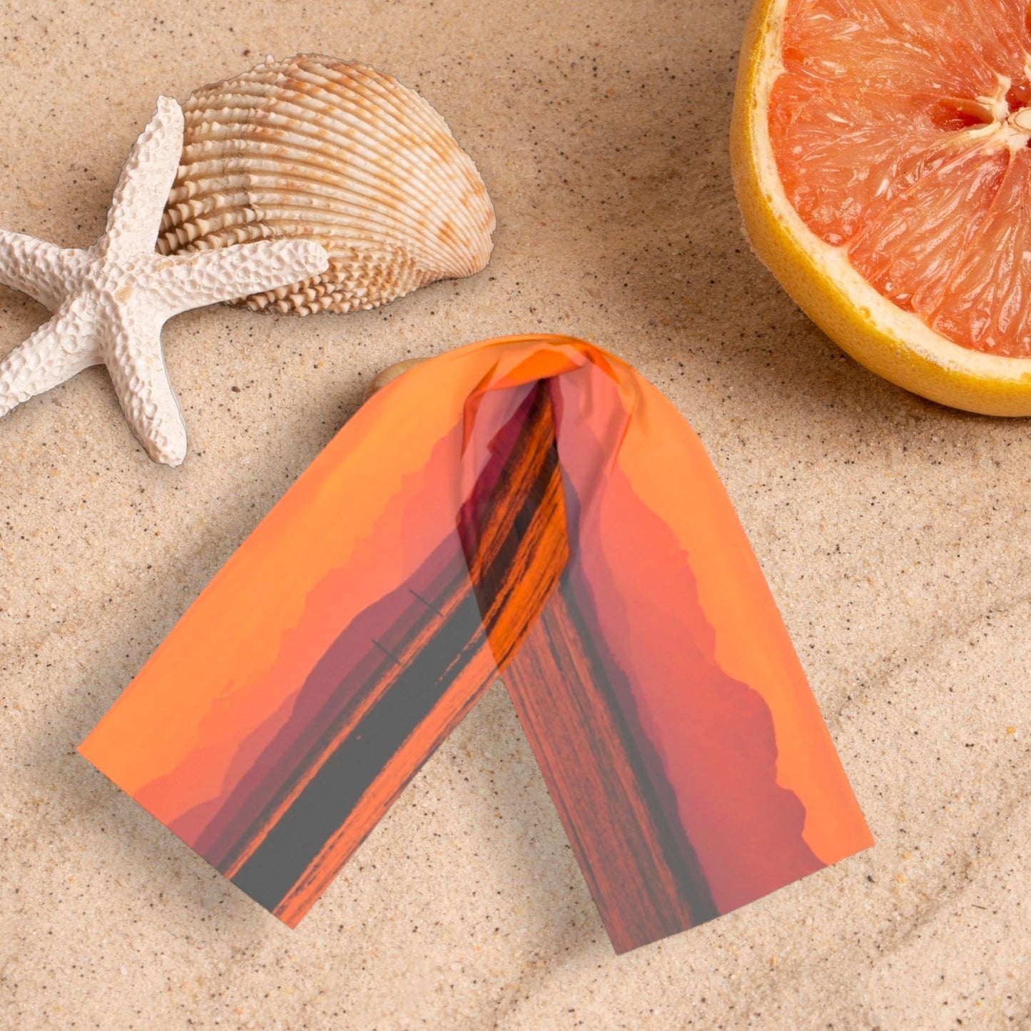 Saratoga Beach Sunset long scarf shown on the sand with seashells and fruit.