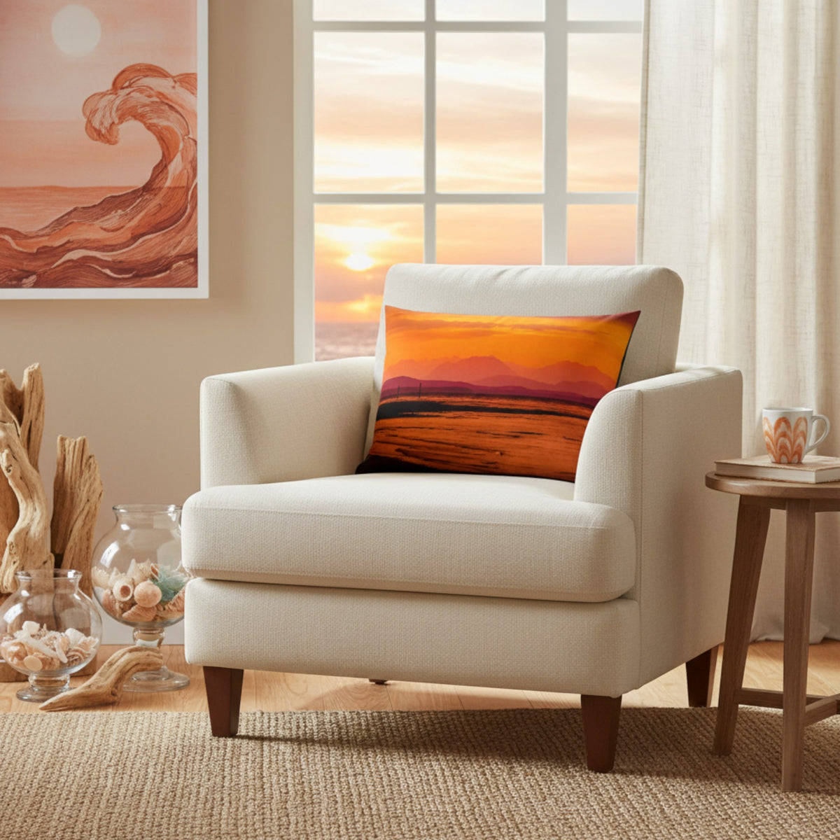 A cream upholstered armchair in a bright living room setting, styled with a square throw pillow featuring a vibrant orange and yellow sunset landscape print.
