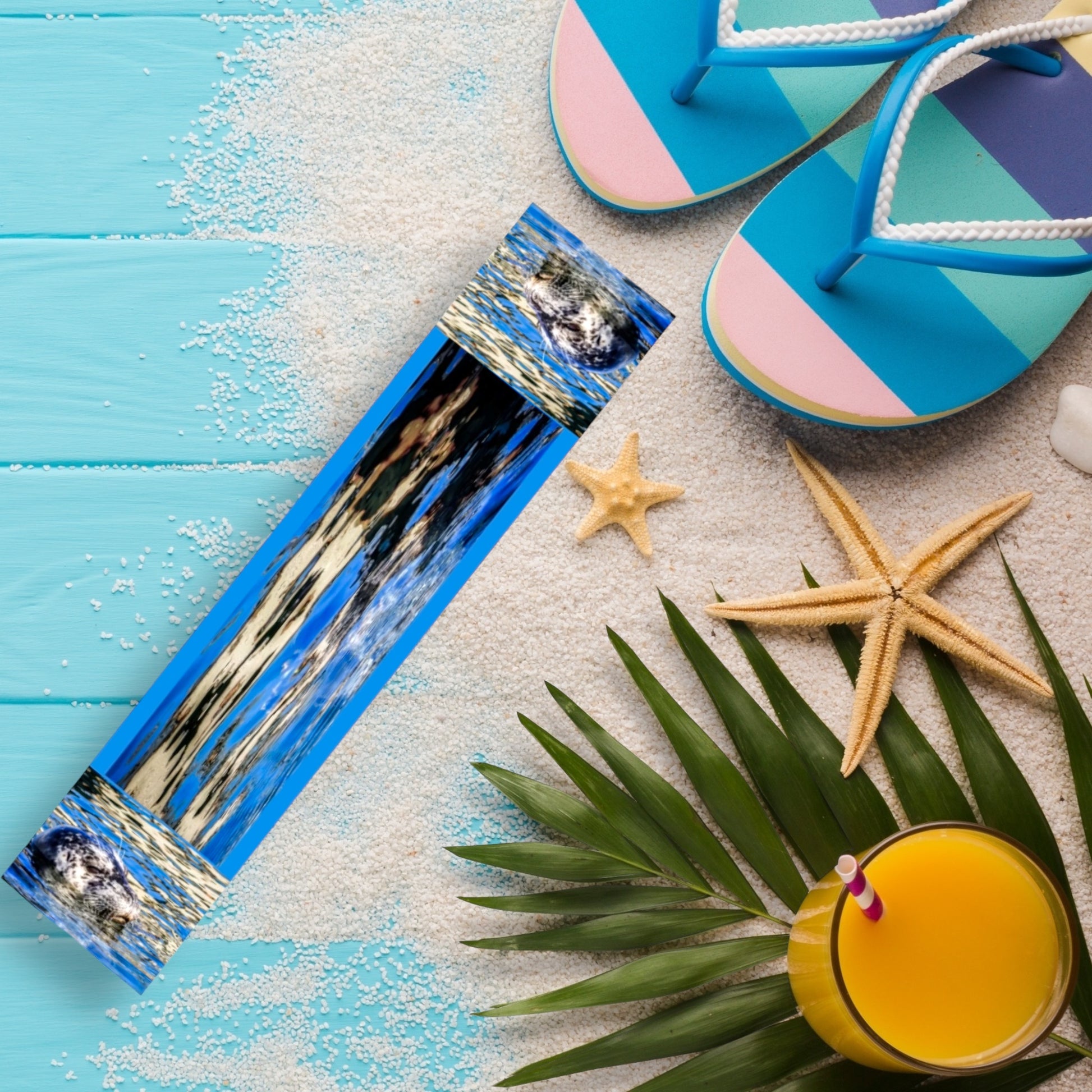 Seal of blue long scarf is shown with a pair of sandals, starfish and a drink.