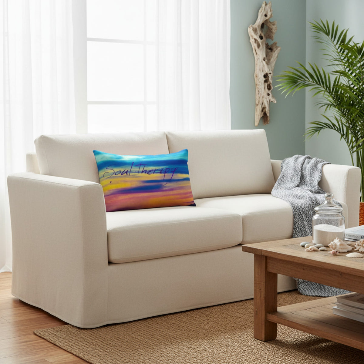 A cream-colored fabric loveseat sofa in a bright, modern living room setting, styled with a colorful abstract print throw pillow that reads 'feel the joy'.