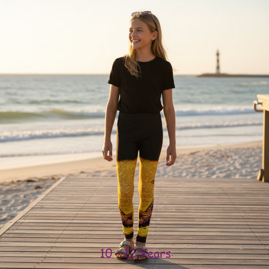 Young girl standing on a wooden boardwalk by the ocean wearing a black t-shirt and yellow leggings.