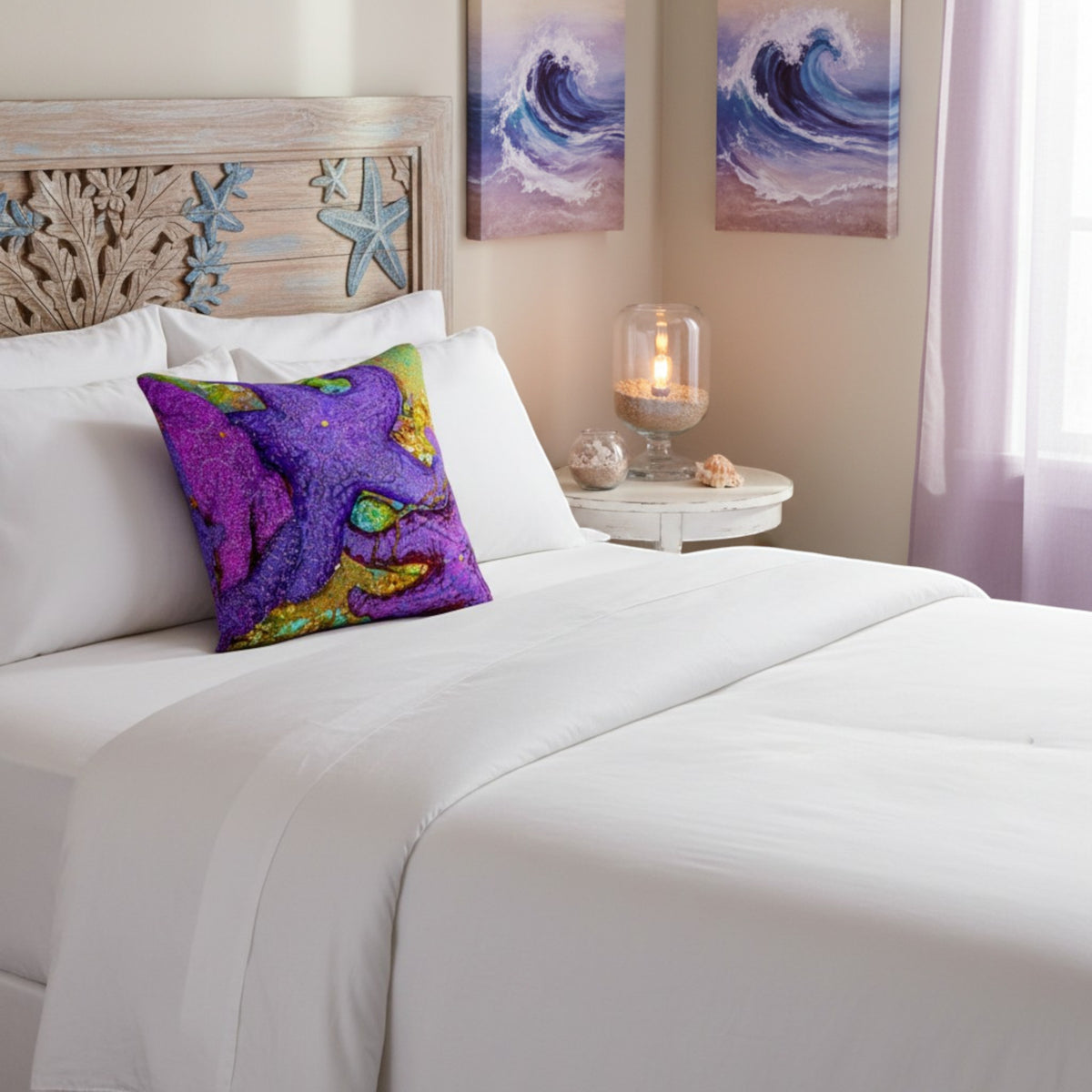 A white made bed in a bedroom setting with a colorful decorative throw pillow featuring a purple octopus design. The room includes a carved wooden headboard, two wave paintings on the wall, and a bedside table with a lit candle.
