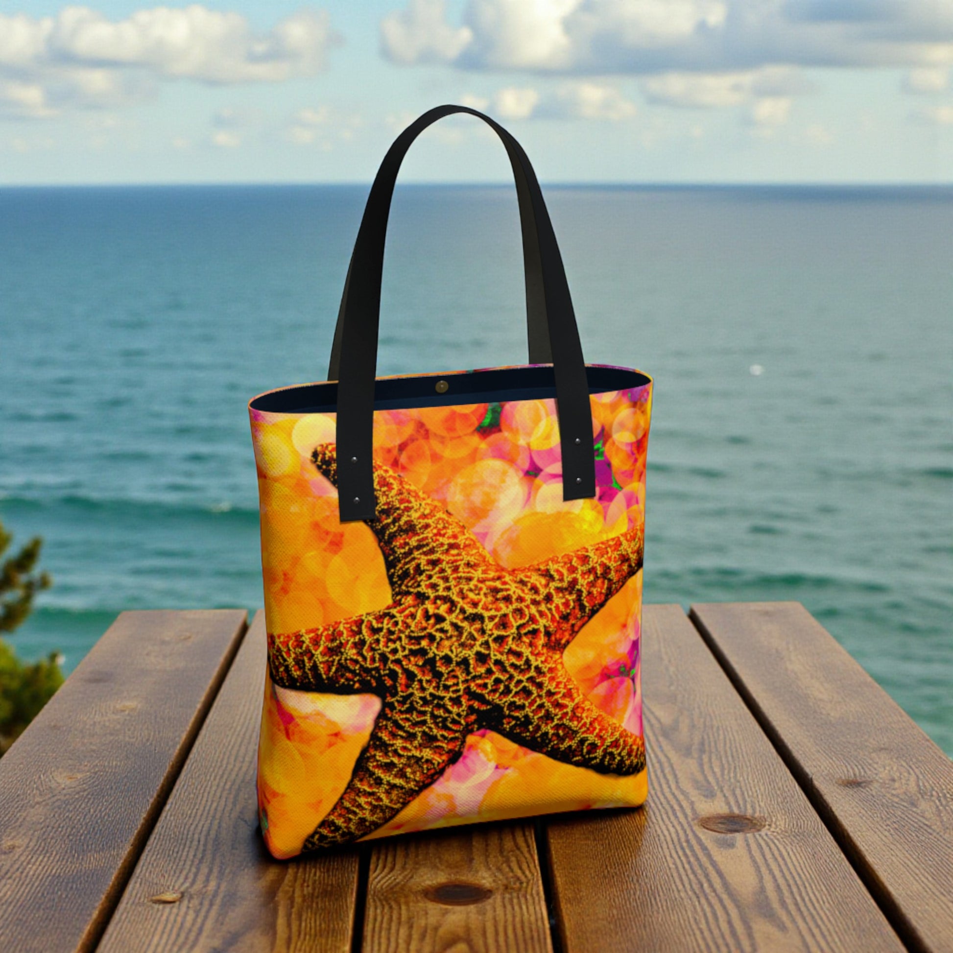 Colorful tote bag with starfish design on a wooden platform by the ocean
