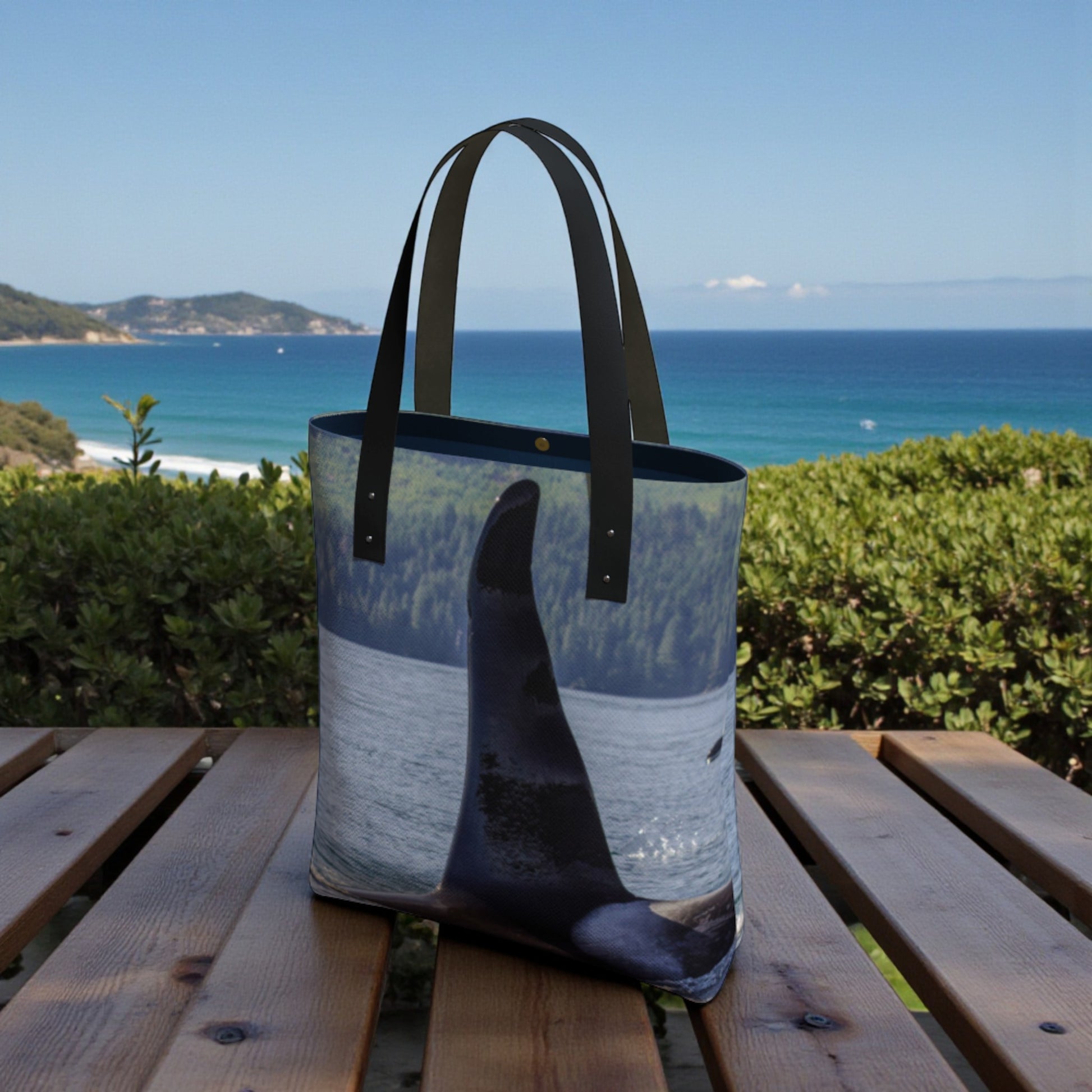 Tote bag with whale design on a wooden bench by the ocean