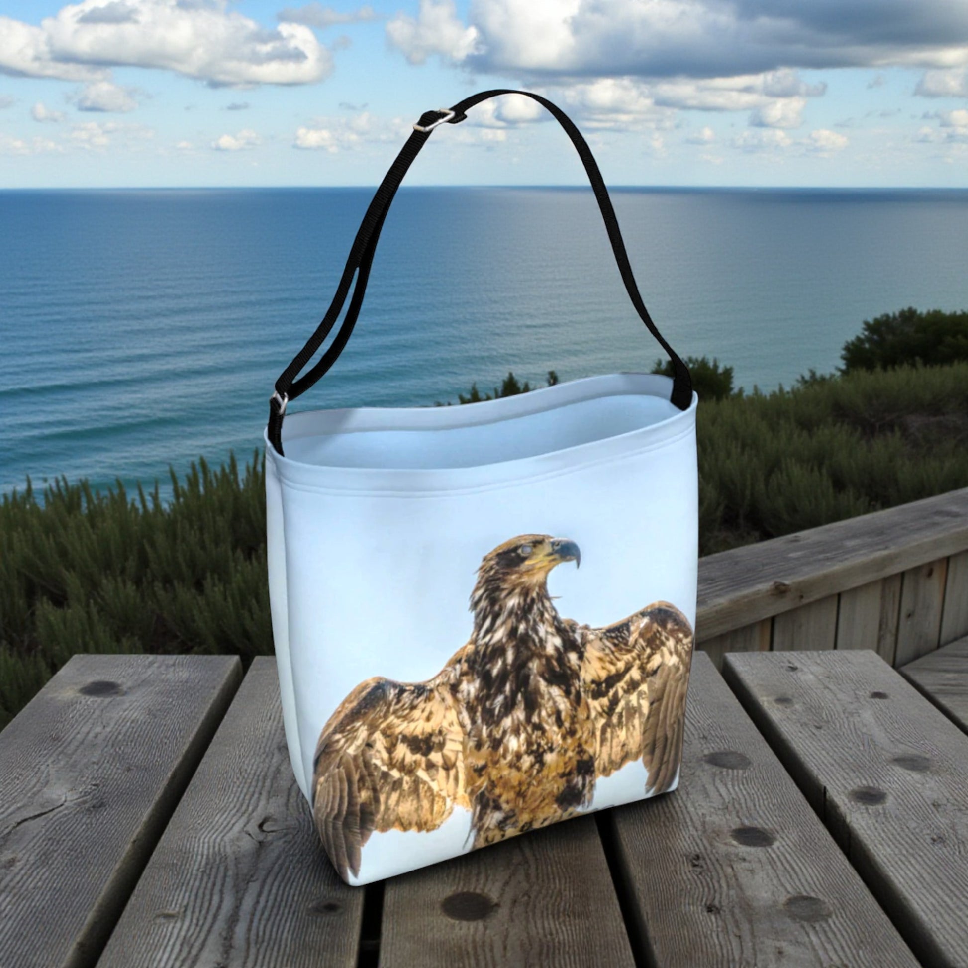 Tote bag with an eagle design on a wooden surface with ocean view