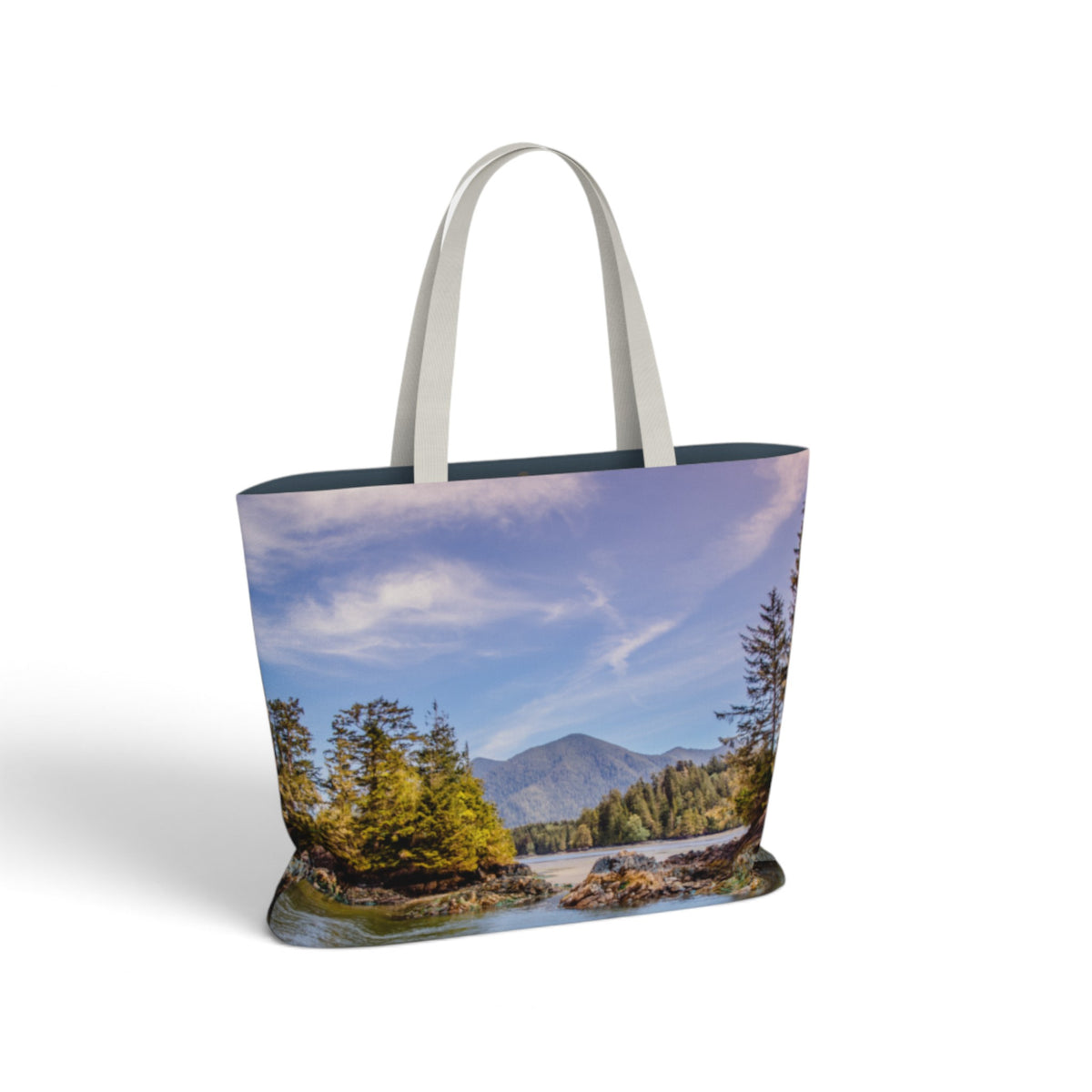 A tote bag with a scenic landscape print of a river, trees, and mountains under a blue sky, featuring light gray shoulder straps, shown on a white background.