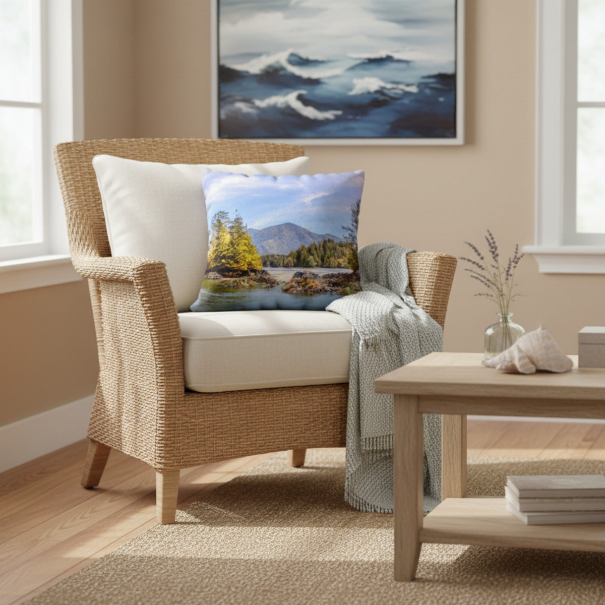 A square decorative throw pillow featuring a scenic landscape print of a mountain lake with yellow-green trees, styled on a woven rattan armchair in a warm beige living room.