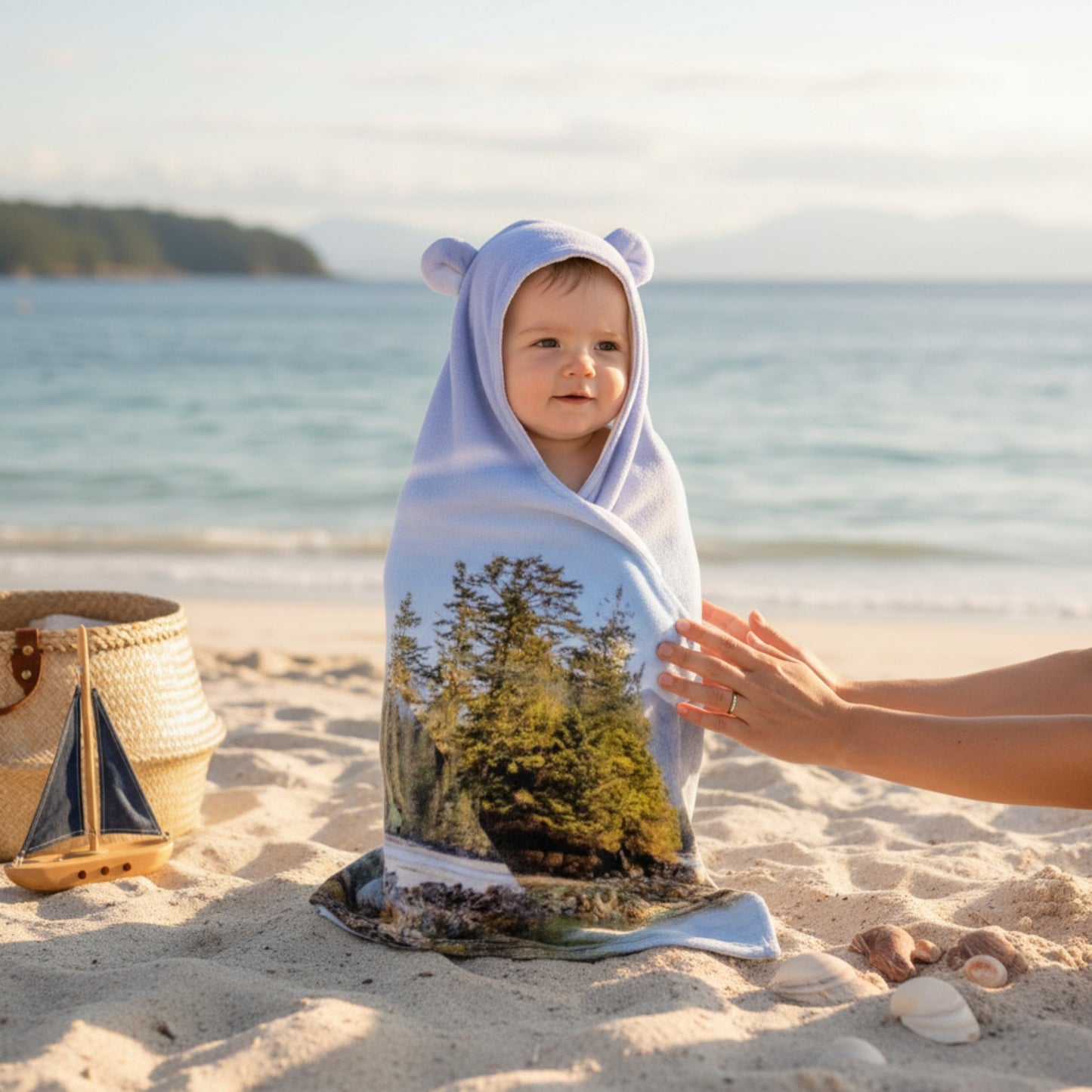 Child wrapped in a towel with a forest design on a beach