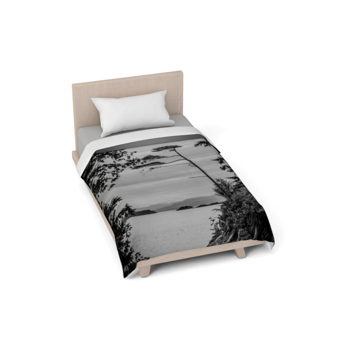 A single bed with a light wood frame and a white pillow, shown on a clean white background. The bed is covered with a duvet or comforter featuring a black-and-white landscape photograph of a lake with trees.