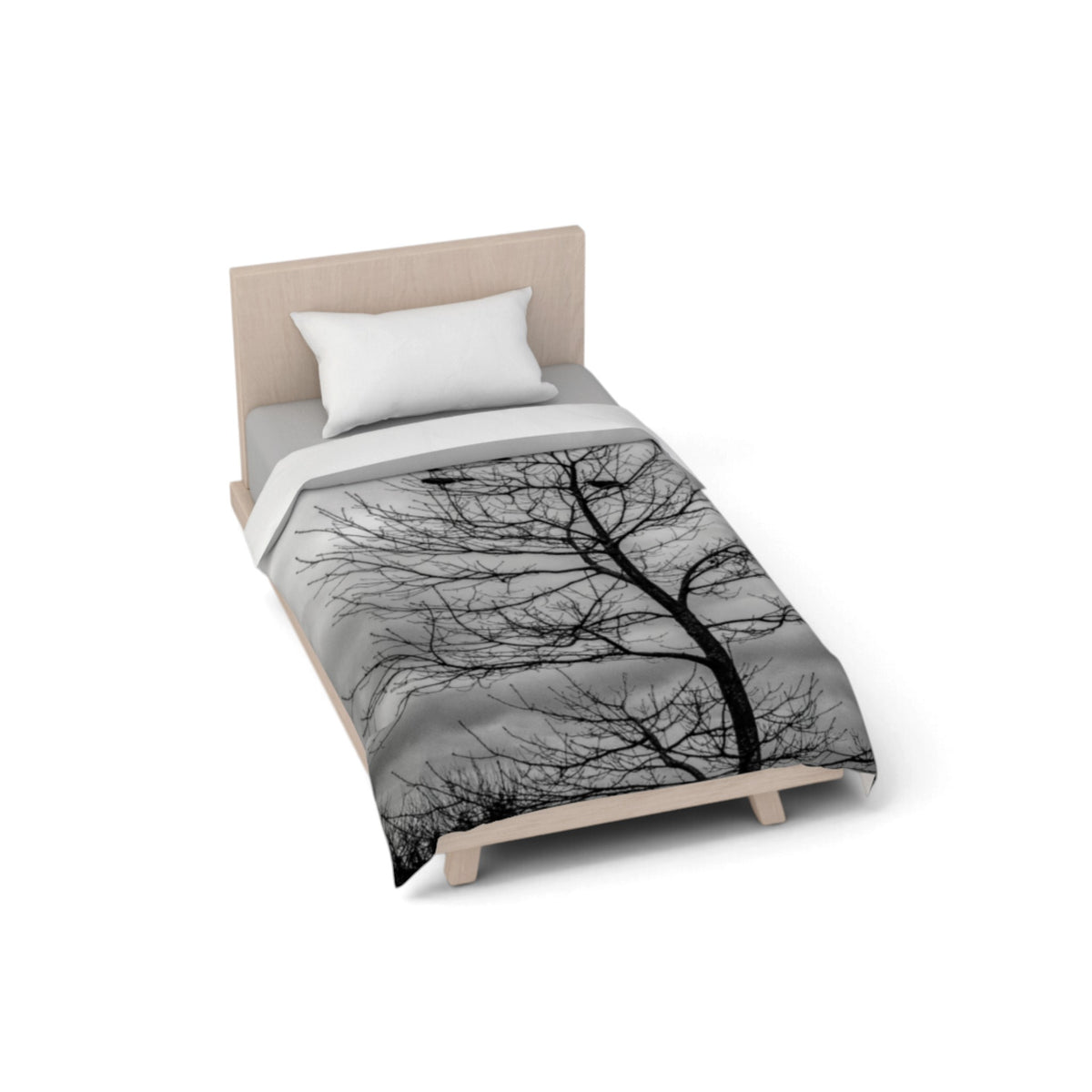 A single bed with a light wood frame and a white pillow, dressed in a gray comforter featuring a black silhouette tree pattern, shown on a plain white background.