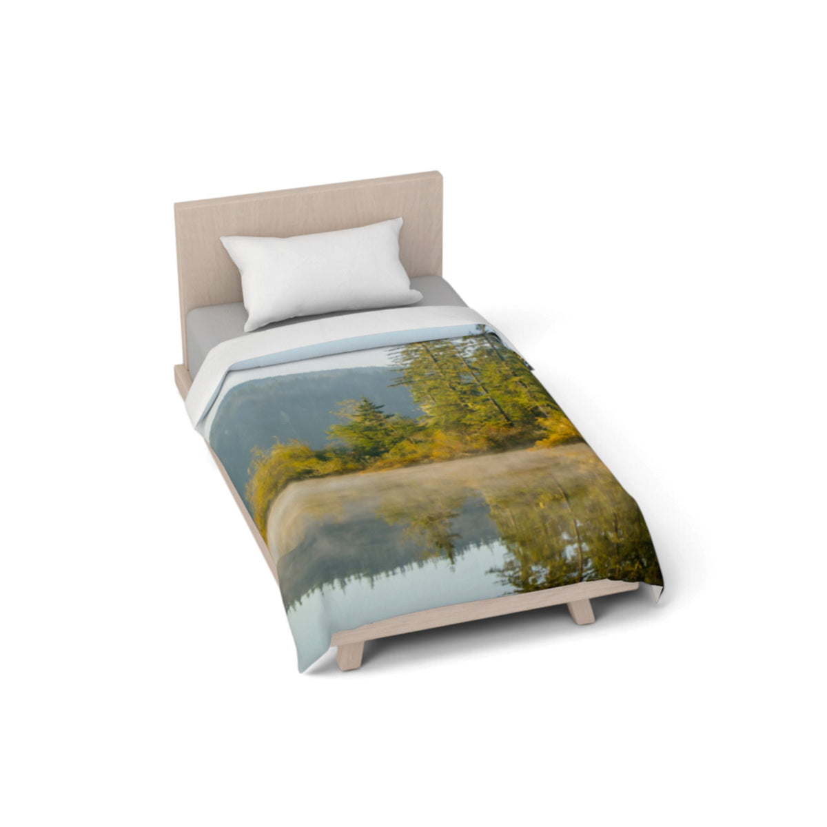 A single bed with a light wood headboard and legs, dressed in a duvet cover featuring a scenic landscape print of a lake and trees, shown on a plain white background.