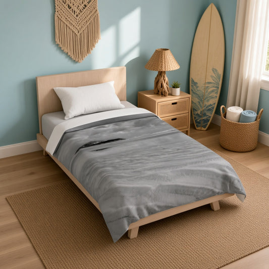 A single bed in a styled bedroom with a gray textured throw blanket, white pillow, and light wood frame, set against a blue wall with a nightstand, lamp, surfboard, and woven decor.