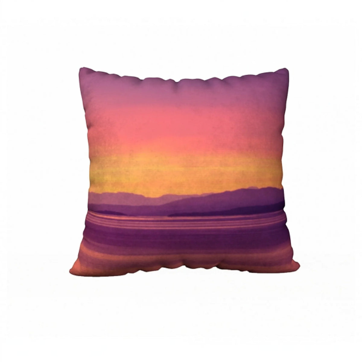 A square throw pillow featuring a scenic sunset landscape print with purple mountains, a yellow and orange horizon, and a pink-to-purple sky, shown against a plain white background.