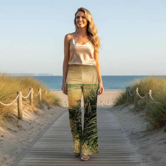 Woman wearing a pants with a beach and grass design on a wooden path.