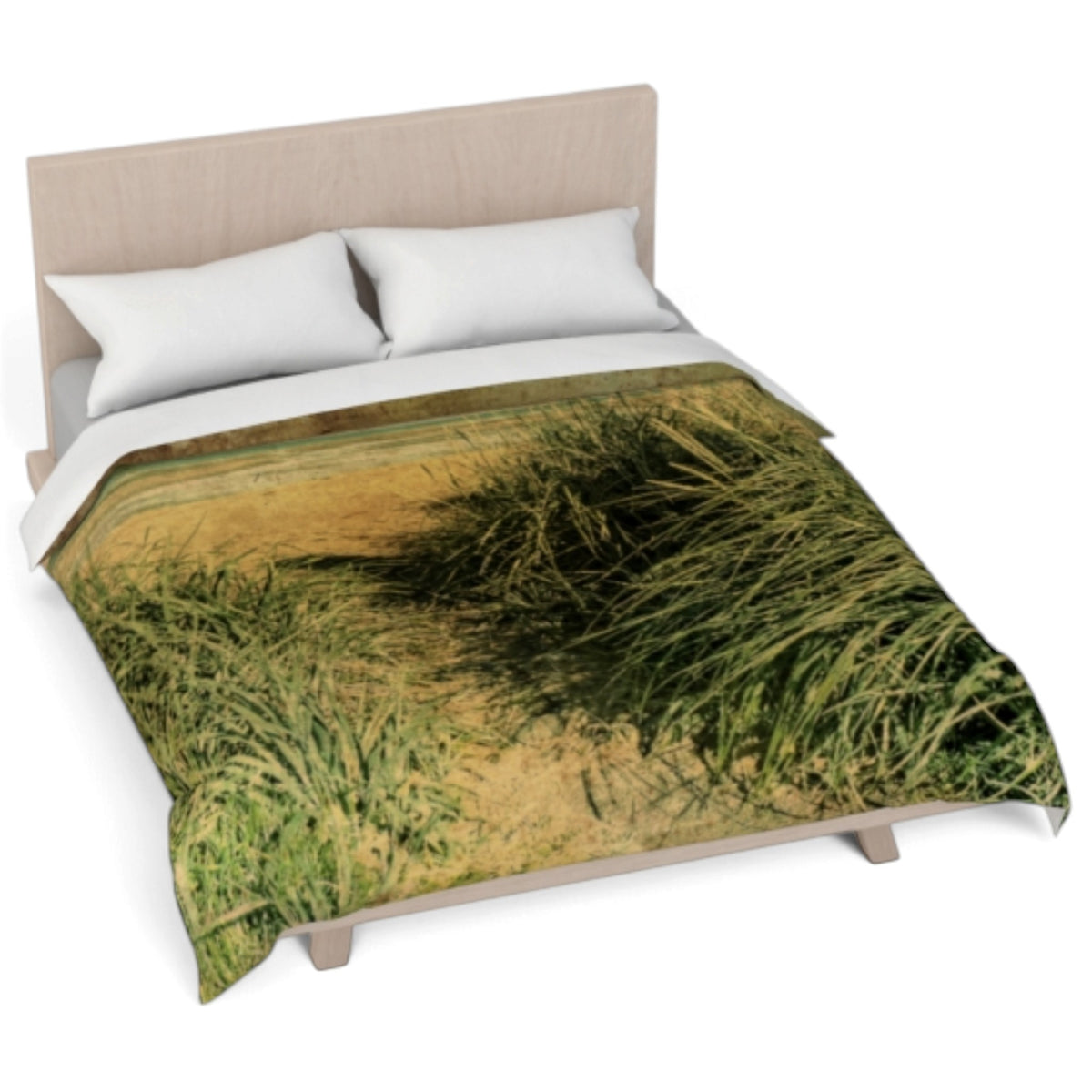 A bed dressed with a comforter featuring a printed dune grass scene in green and yellow tones, styled with two white pillows against a light wood headboard on a white background.