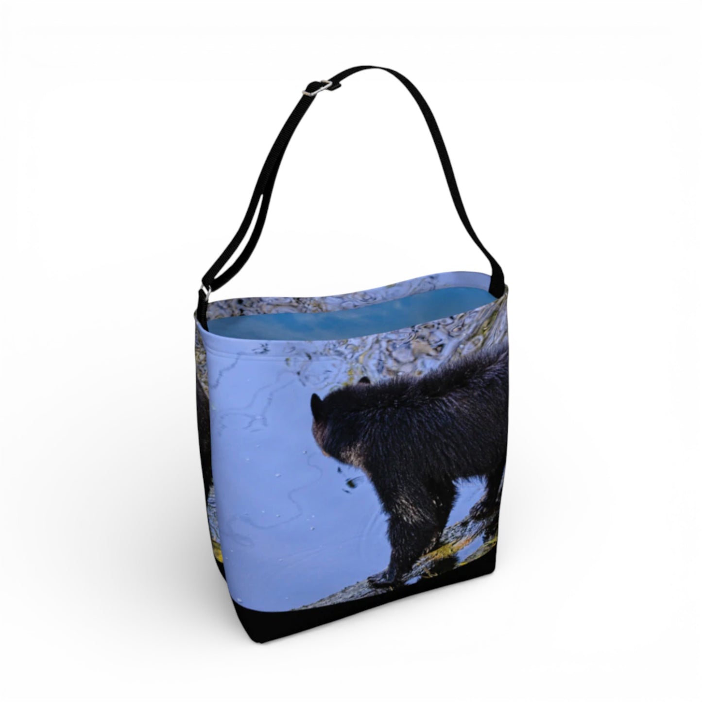 Tote bag with a design of a black bear in a blue landscape on a white background