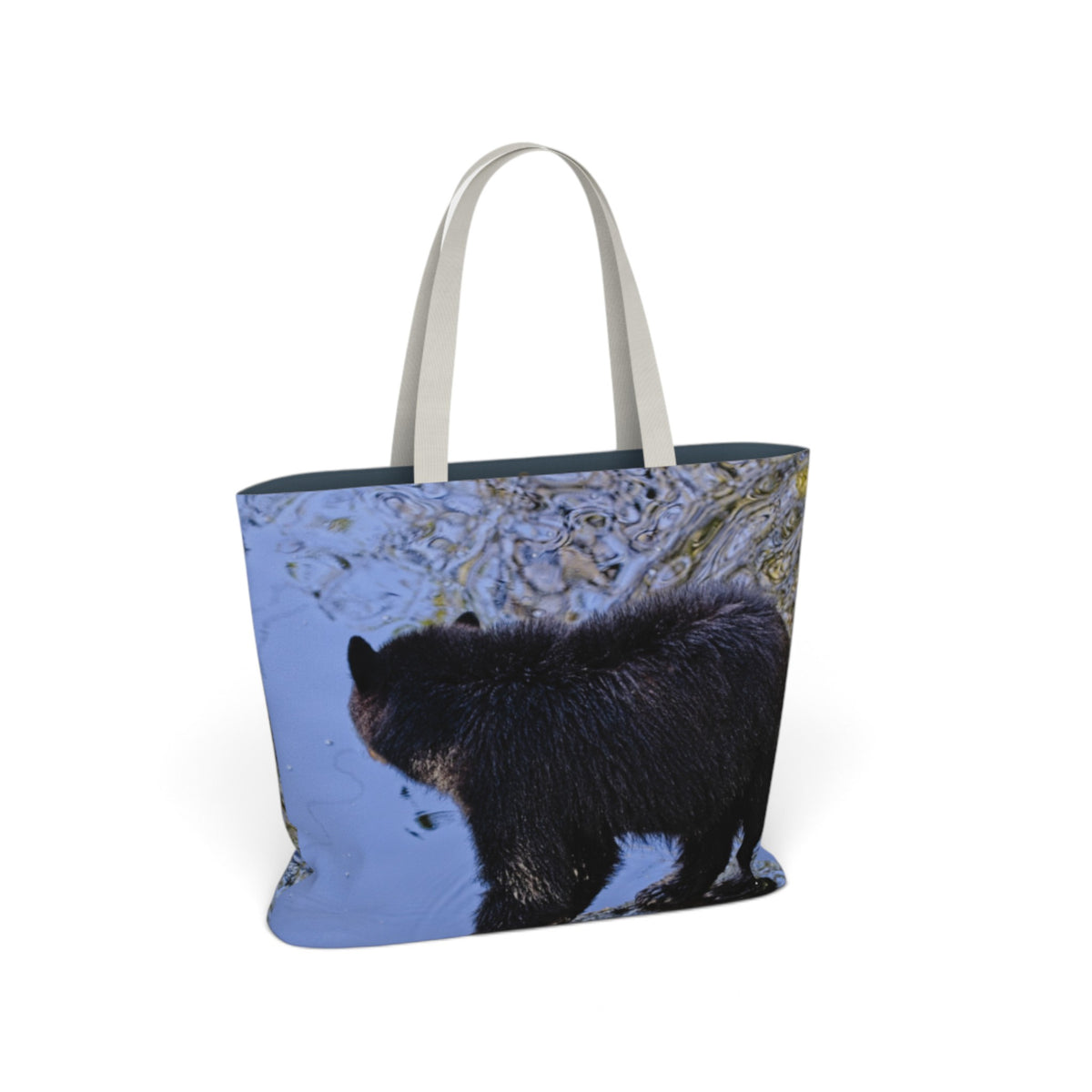 A tote bag with a photographic print of a black bear standing in blue water, featuring light gray shoulder straps, shown on a plain white background.