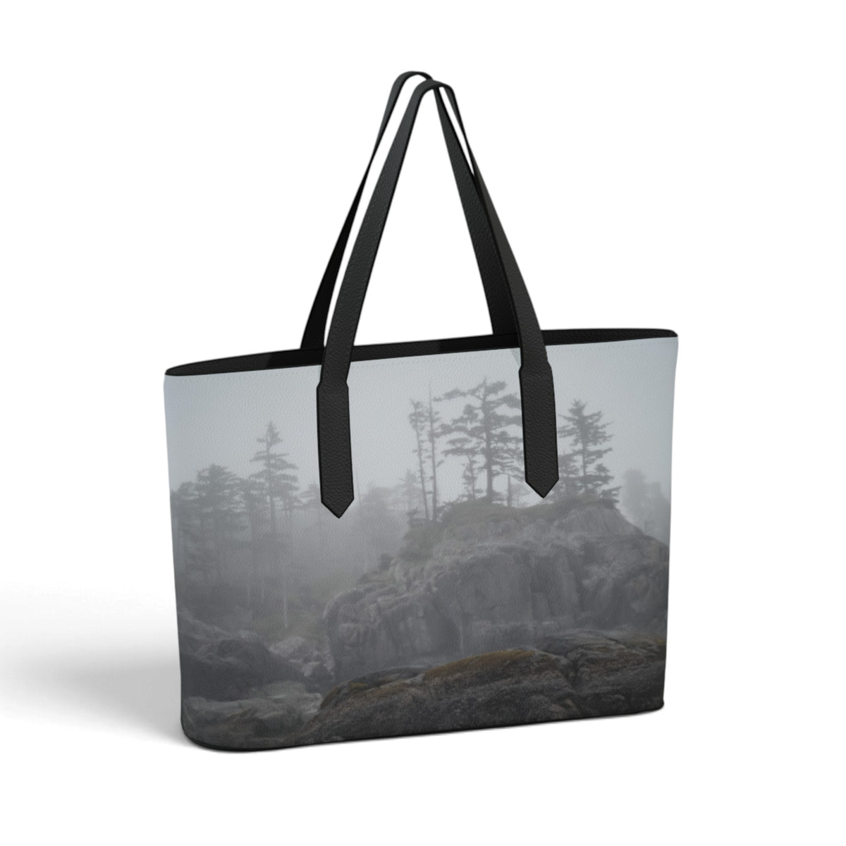 A large tote bag featuring a printed foggy forest and rocky landscape design, with black shoulder straps and black trim, shown on a plain white background.
