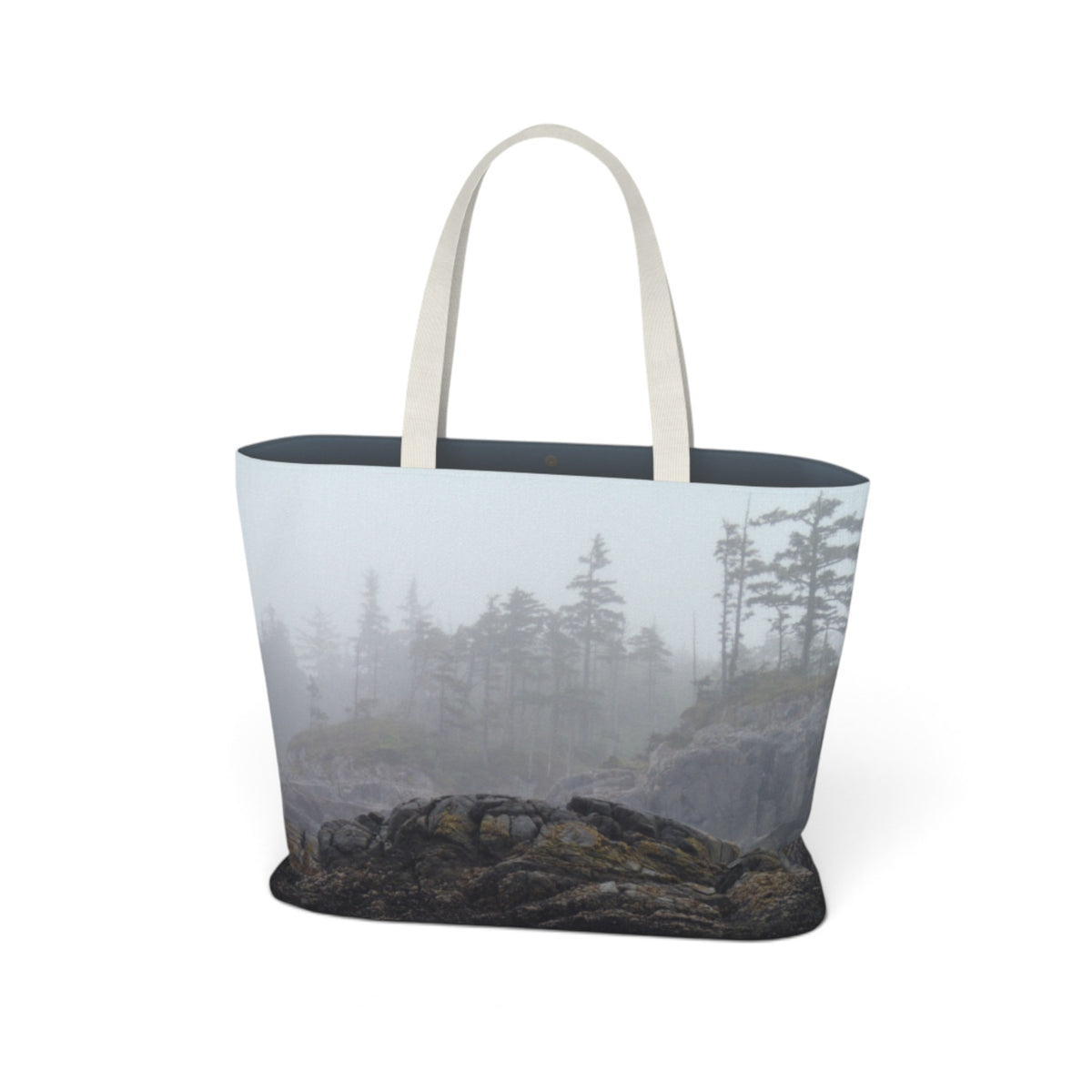 A tote bag featuring a photographic print of a misty pine forest on the front, with a dark navy blue interior lining and off-white shoulder straps, shown against a plain white background.