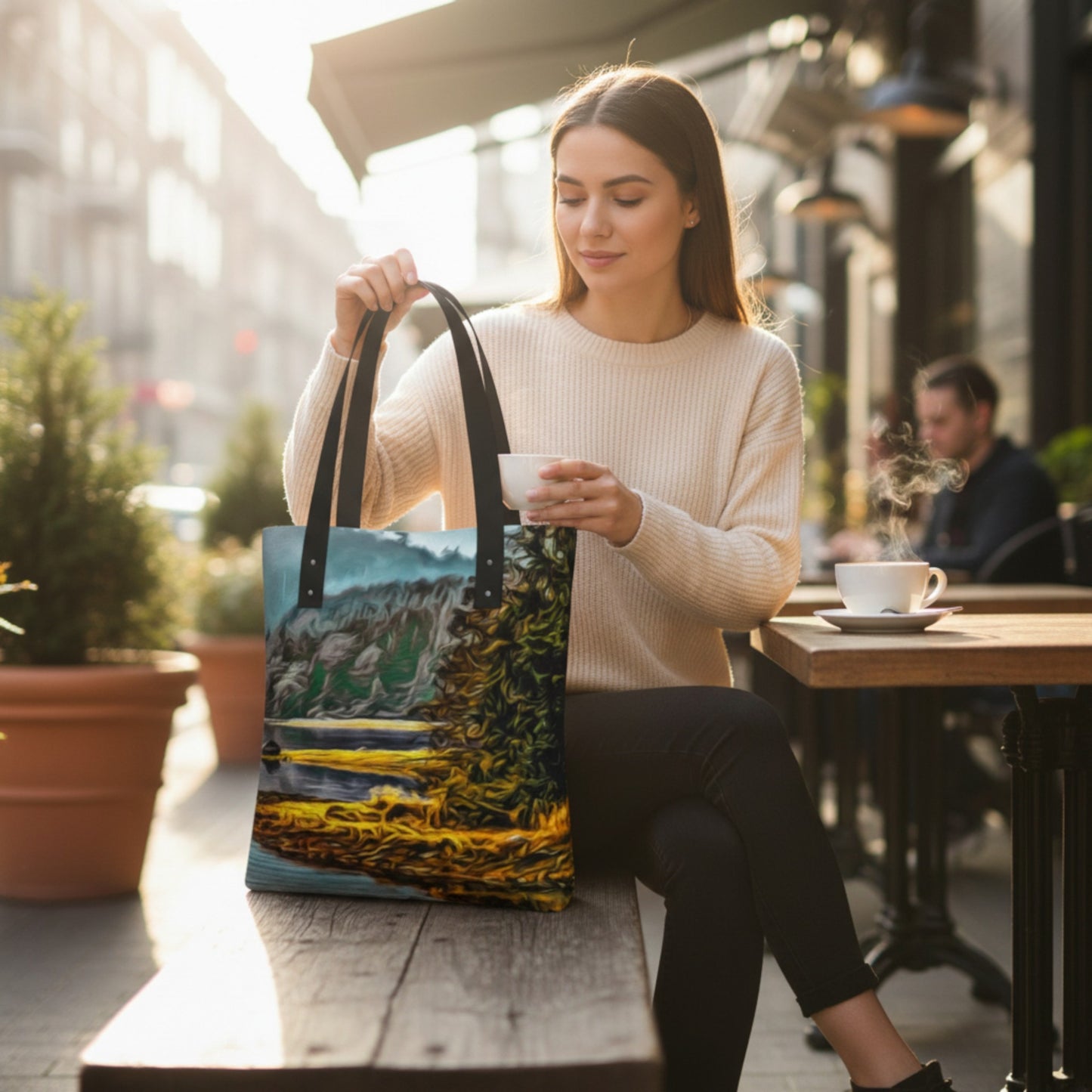 Woman holding a scenic tote bag and a cup of coffee outdoors.