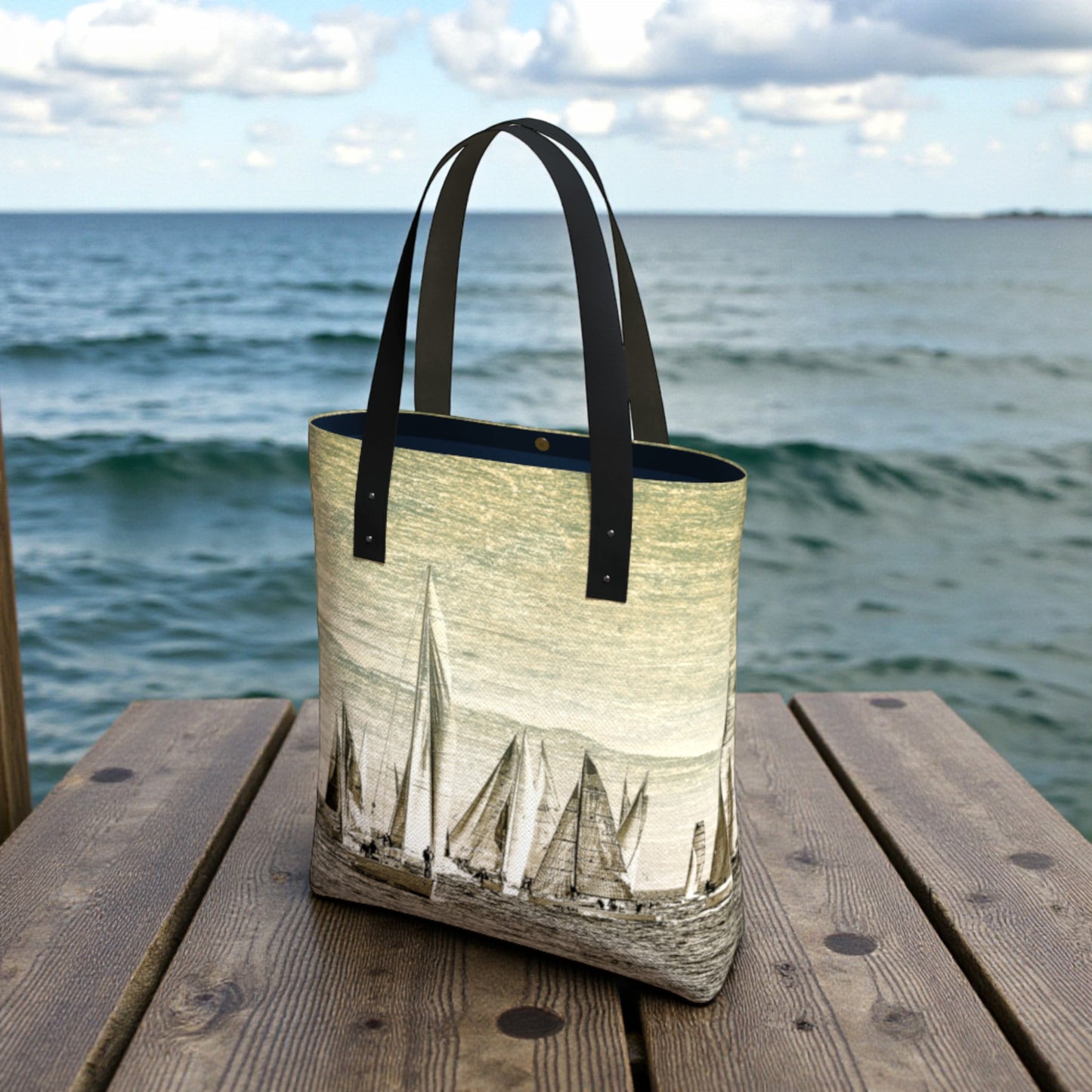 Tote bag with sailboat design on a wooden dock by the ocean
