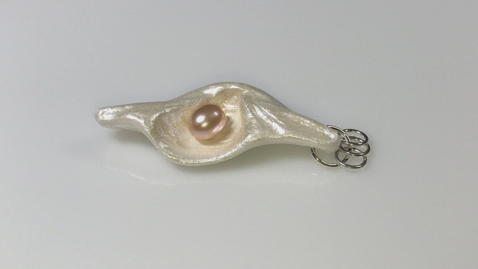 A video showing Glow natural seashell pendant with a pink freshwater pearl. 