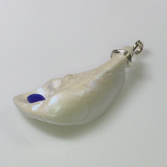 The cobalt natural seashell pendant with blue sea glass is shown in a complete circle so the viewer can see the pendant in its entirety.