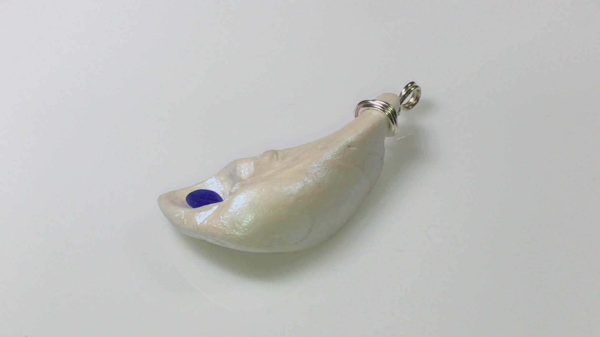 The cobalt natural seashell pendant with blue sea glass is shown in a complete circle so the viewer can see the pendant in its entirety.