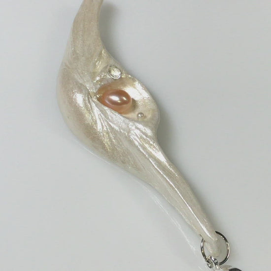 A video showcasing Nefertiti natural seashell and a real 8 mm pink freshwater Pearl, a baby pearl and a 5mm faceted Herkimer diamond compliments the pendant.