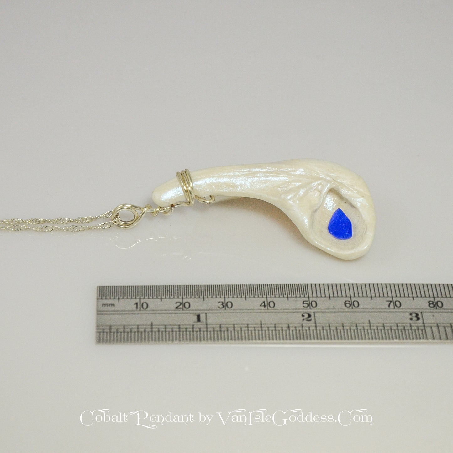 The cobalt pendant is shown on its side along a ruler so the viewer can see the length of the pendant.