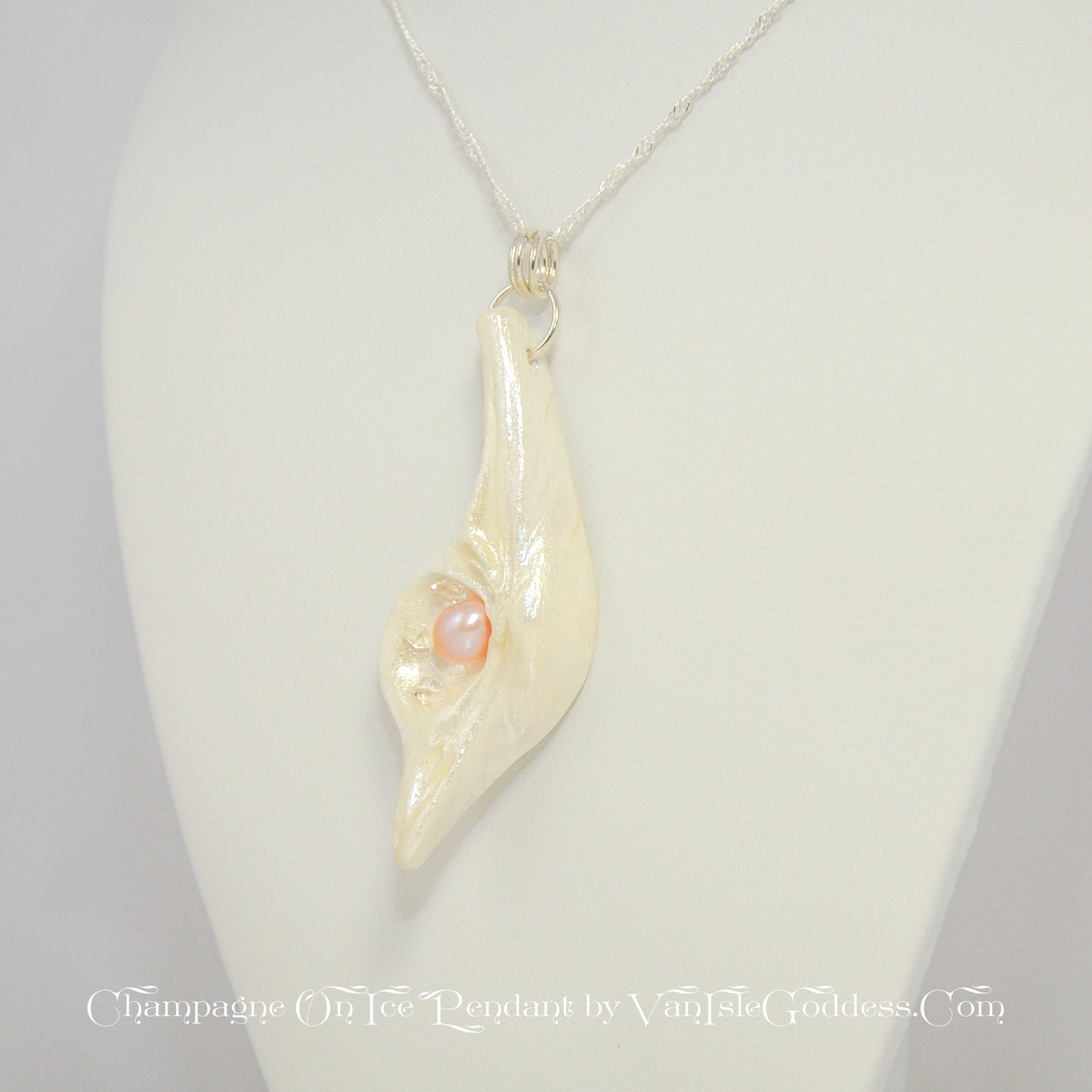 The Champagne on Ice pendant is shown hanging from a necklace.  The pendant is slightly turned to show the left side of the pendant. The print on the bottom of the image says: champagne on ice pendant by van isle goddess dot com