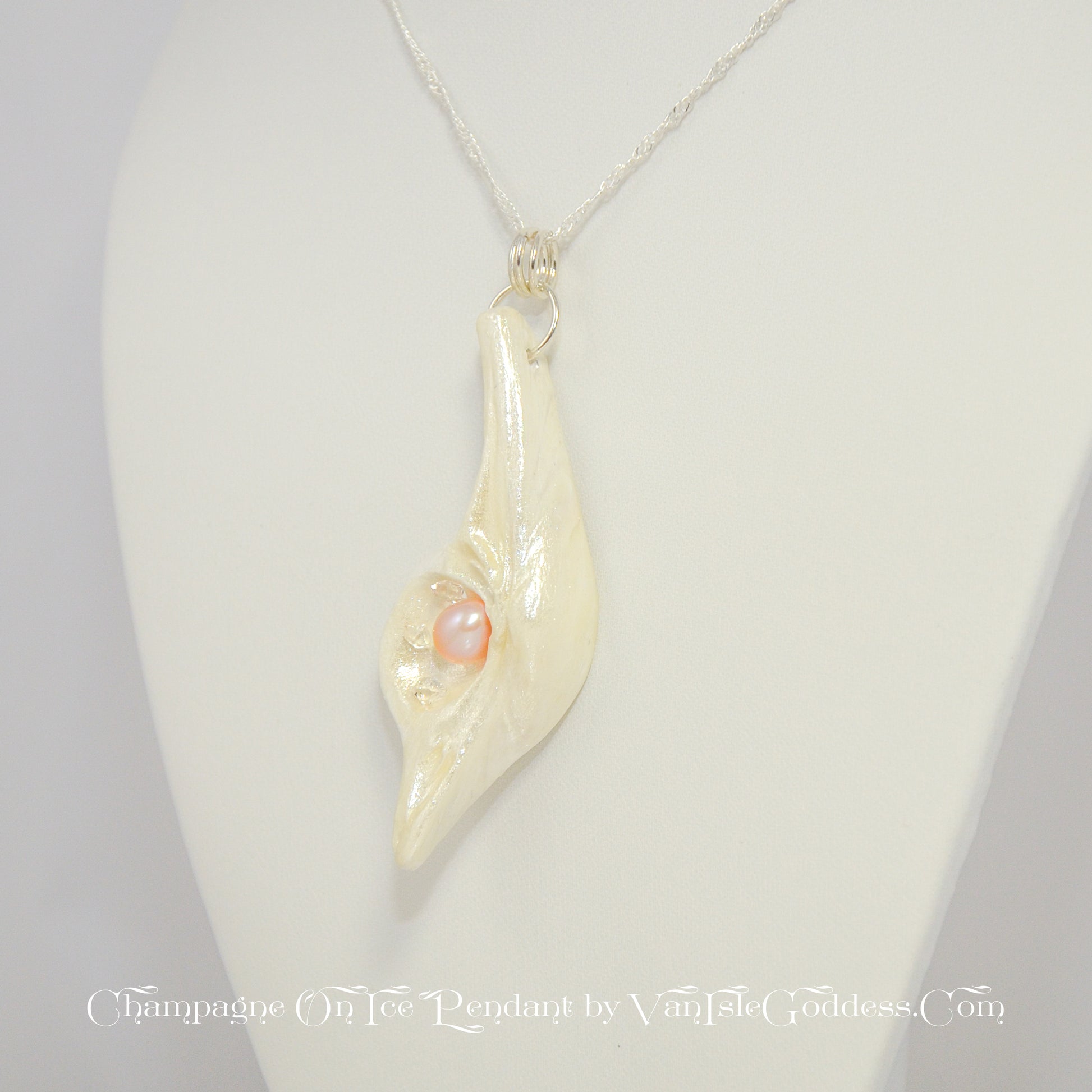 The Champagne on Ice pendant is shown hanging from a necklace.  The pendant is slightly turned to show the left side of the pendant. The print on the bottom of the image says: champagne on ice pendant by van isle goddess dot com