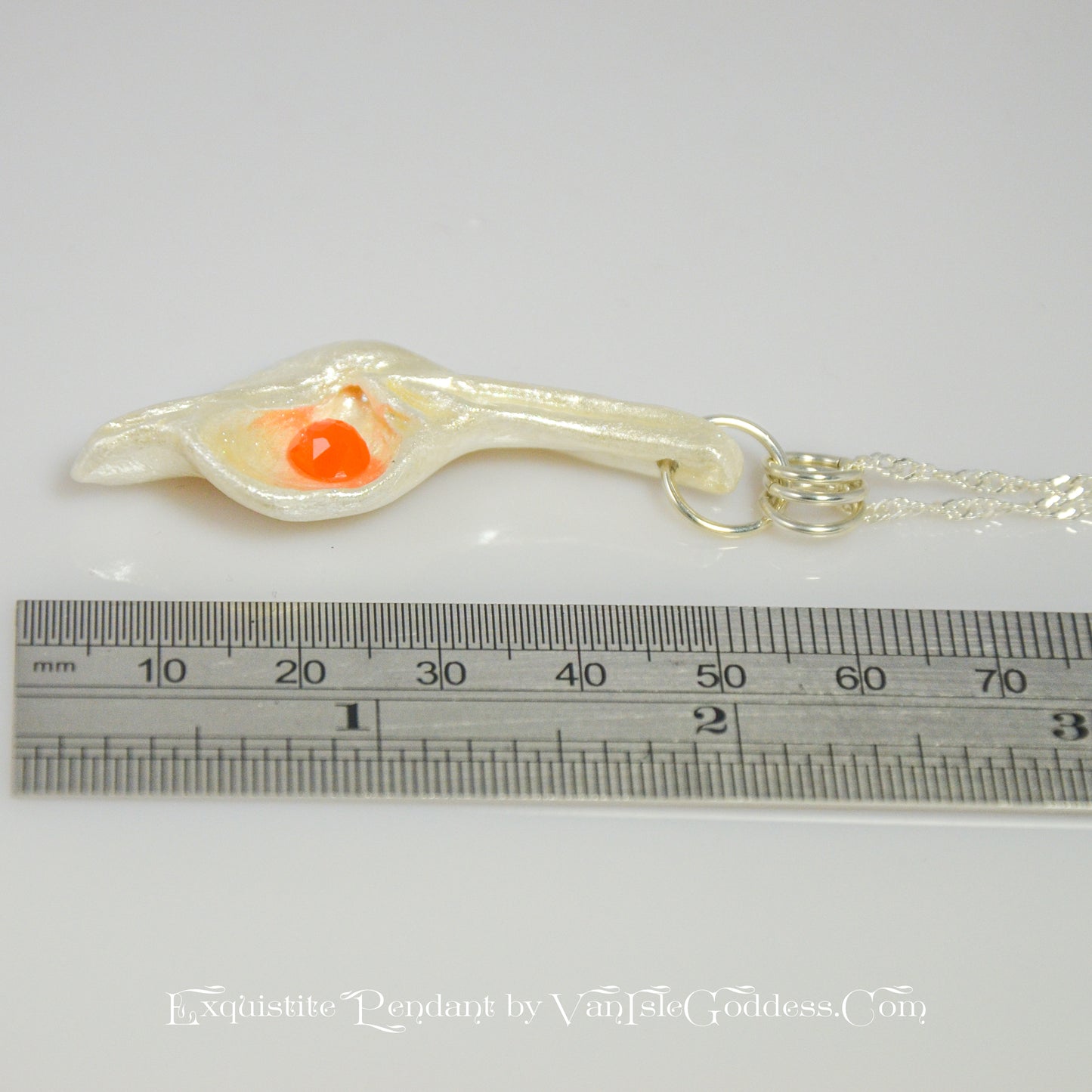 Natural Seashell pendant, elevating the beautiful natural nuances to new heights. The pendant is perfectly adorned with a mesmerizing rose cut Carnelian gemstone. The pendant is laying flat on a table top with a ruler so the viewer can see the length of the pendant.
