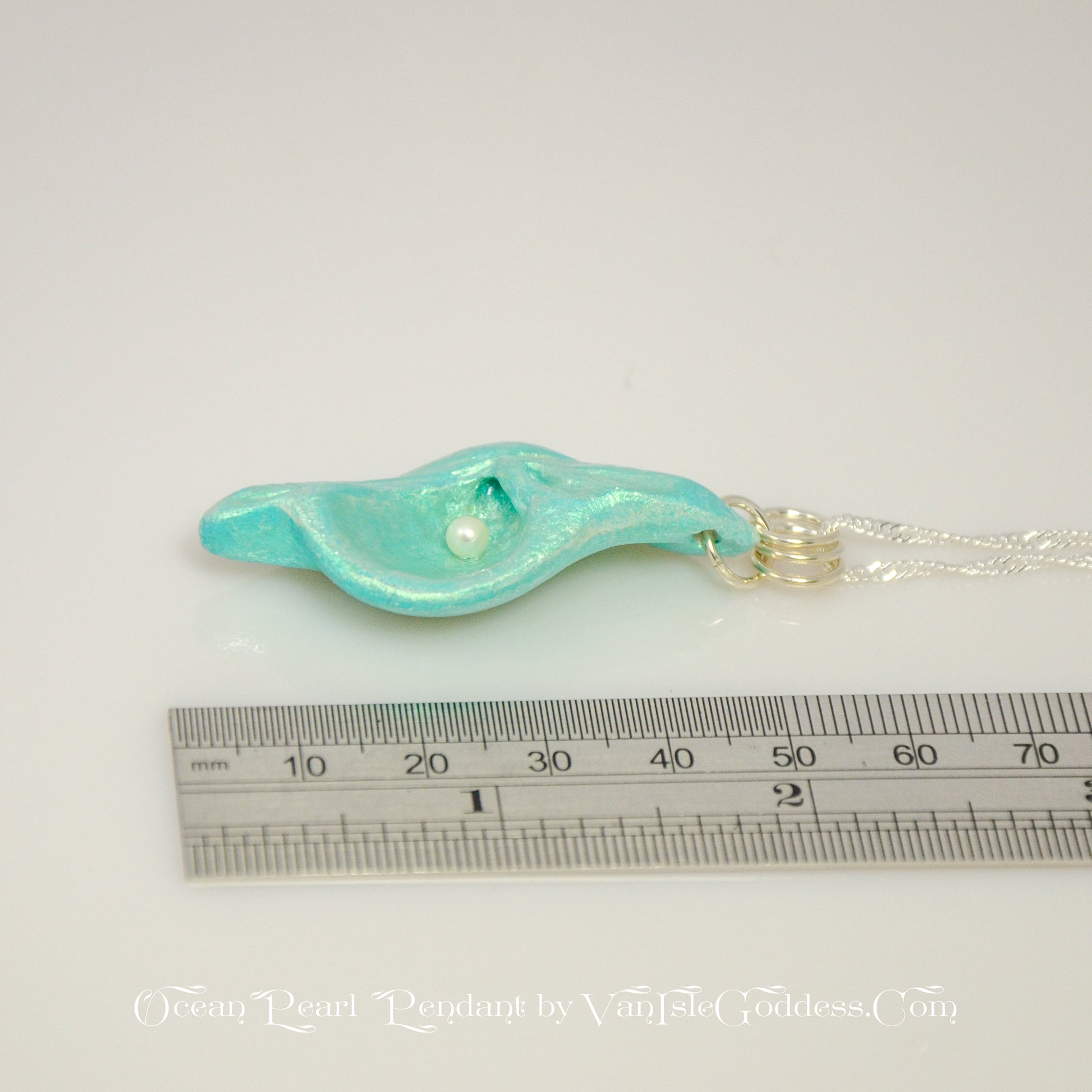 Ocean Pearl natural seashell pendant has a  real freshwater baby pearl. The pendant is shown along side a ruler so the viewer can see how long the pendant is.