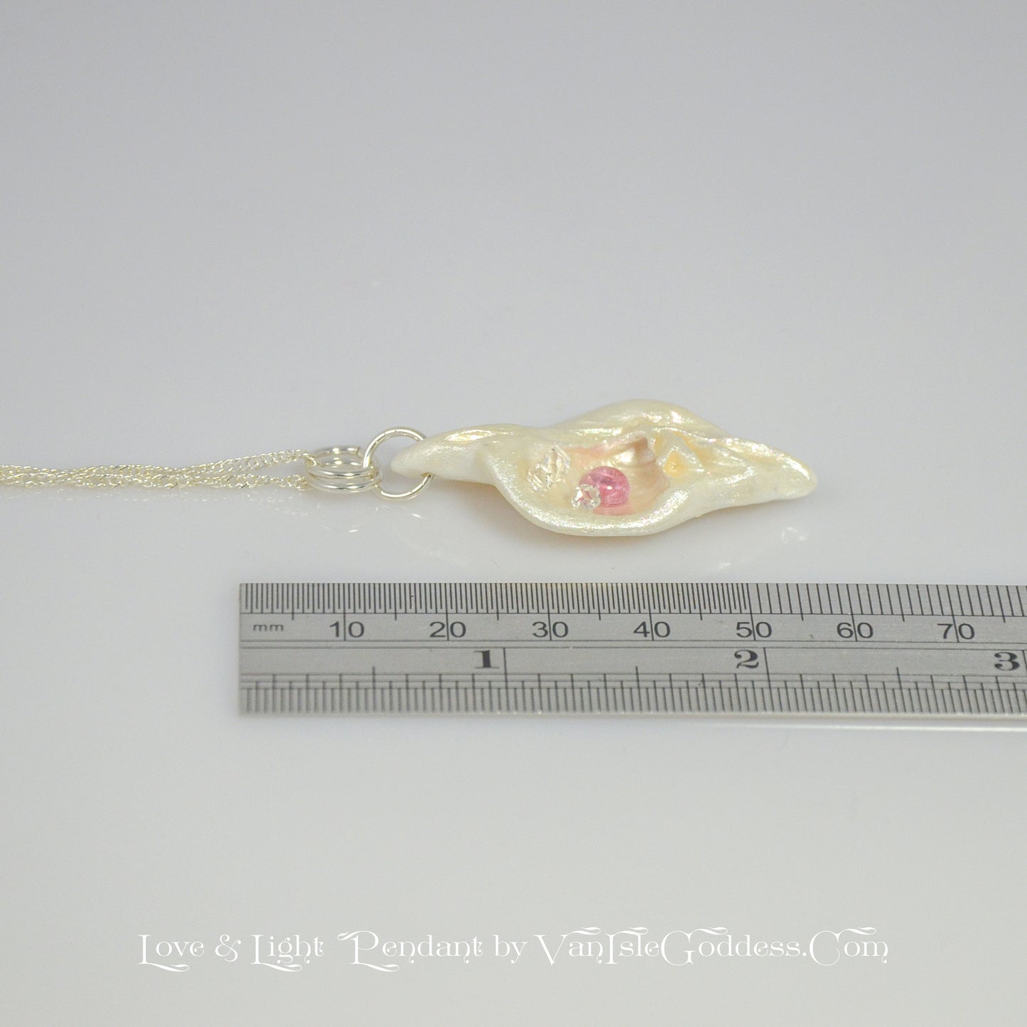 This natural seashell pendant has Pink Tourmaline gemstone and three Herkimer Diamonds that compliments the pendant. The pendant is shown along side a ruler so the viewer can see the length of the pendant.