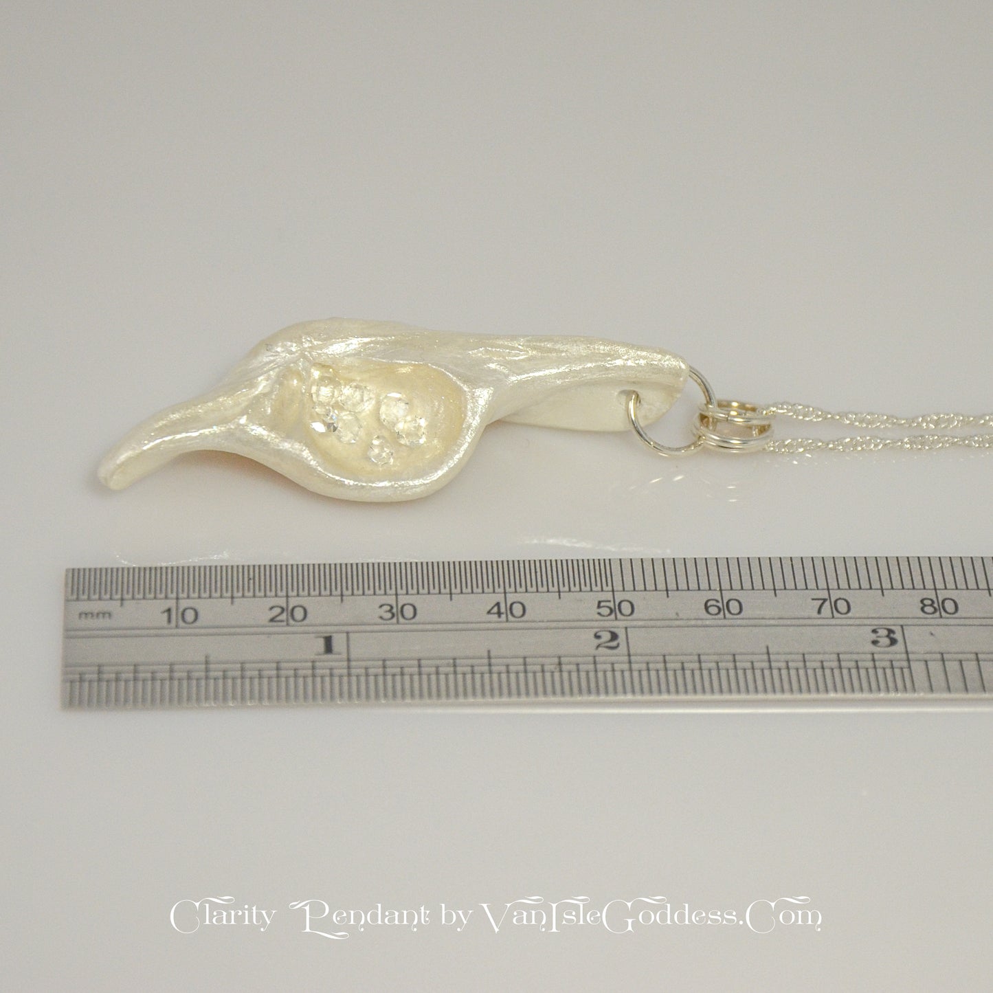 The pendant is shown on its side along a ruler so the viewer can see the length of the pendant.