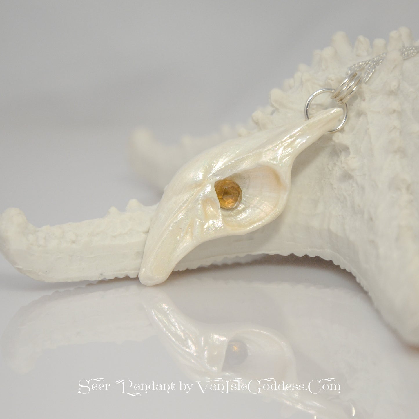 Seer is a natural seashell pendant with a beautiful 5mm rose cut Smokey Quartz compliments the pendant. The pendant is shown resting on a starfish.