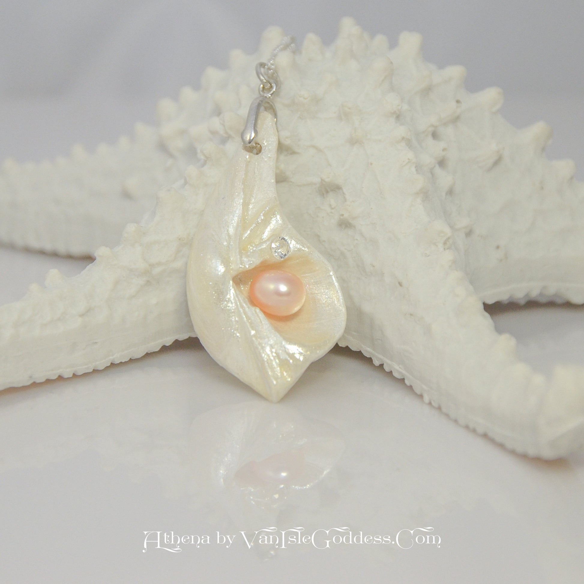 Athena is the name of the pendant being showcased.  It is a natural seashell from the beaches of Vancouver Island. The pendant has a real pink freshwater pearl and a faceted herkimer diamond. It is being showcased on a starfish.
