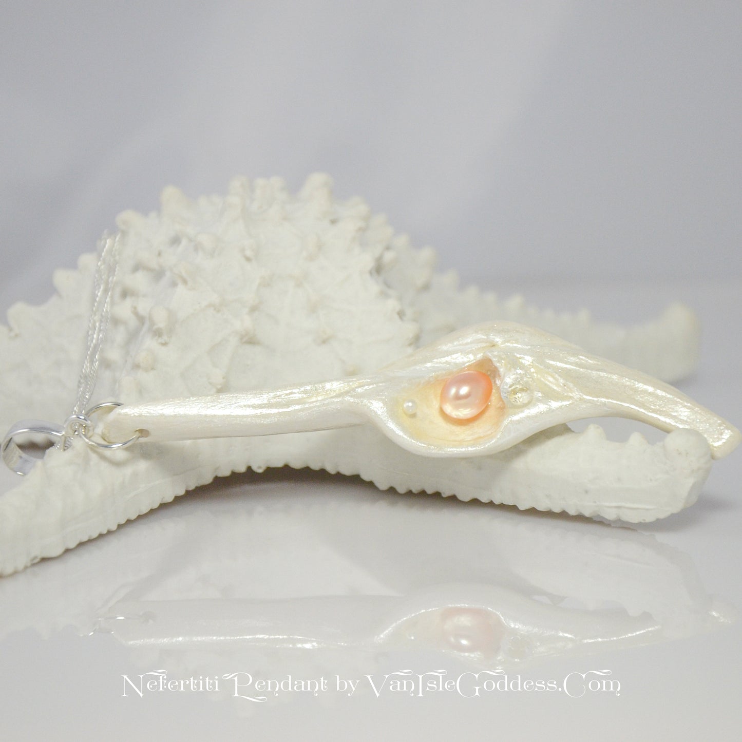 Nefertiti natural seashell and a real 8 mm pink freshwater Pearl, a baby pearl and a 5mm faceted Herkimer diamond compliments the pendant. The pendant rests on a starfish.  The words on the bottom read Nefertiti Pendant by Van Isle Goddess dot com
