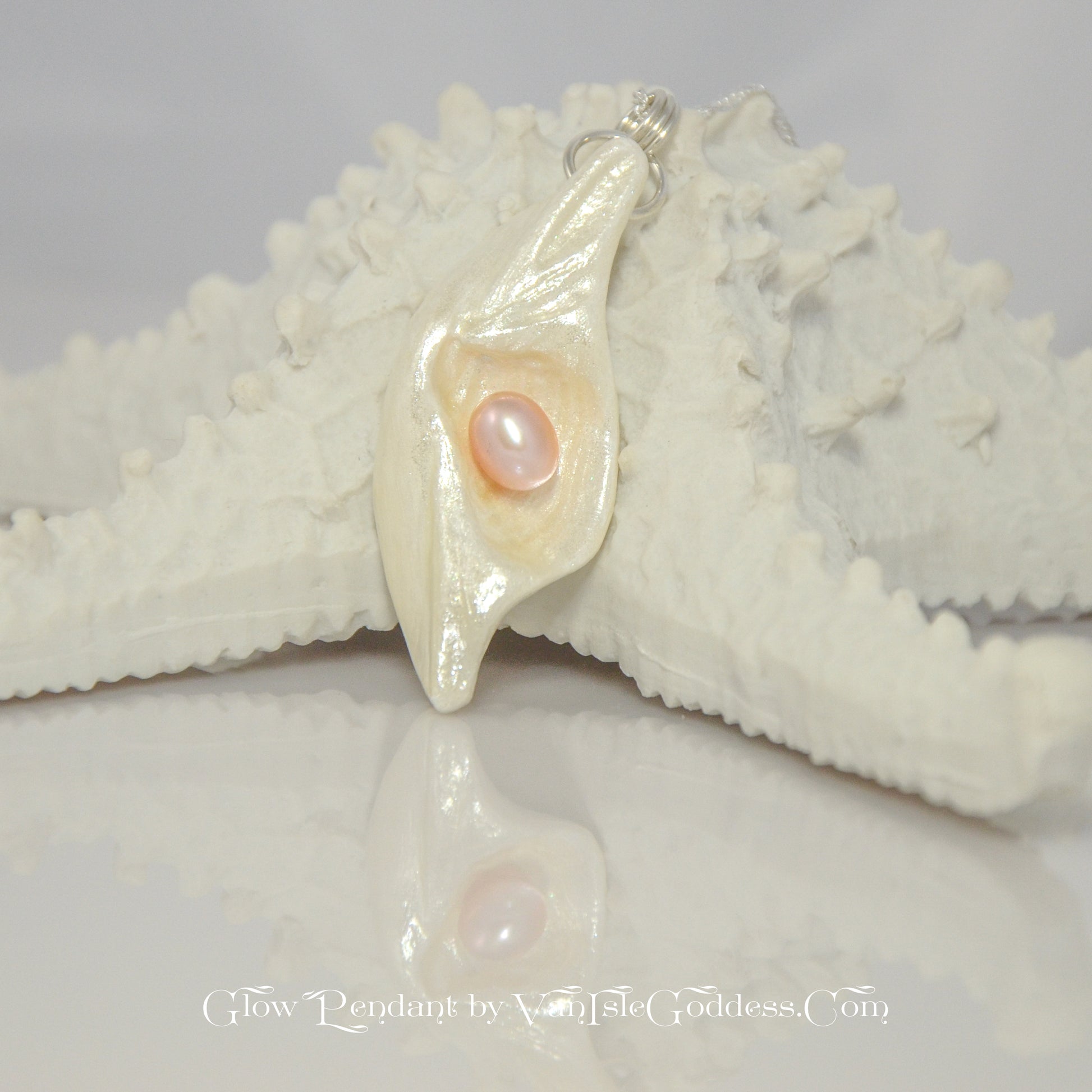 Glow natural seashell pendant with a pink freshwater pearl. The pendant rests on a starfish.